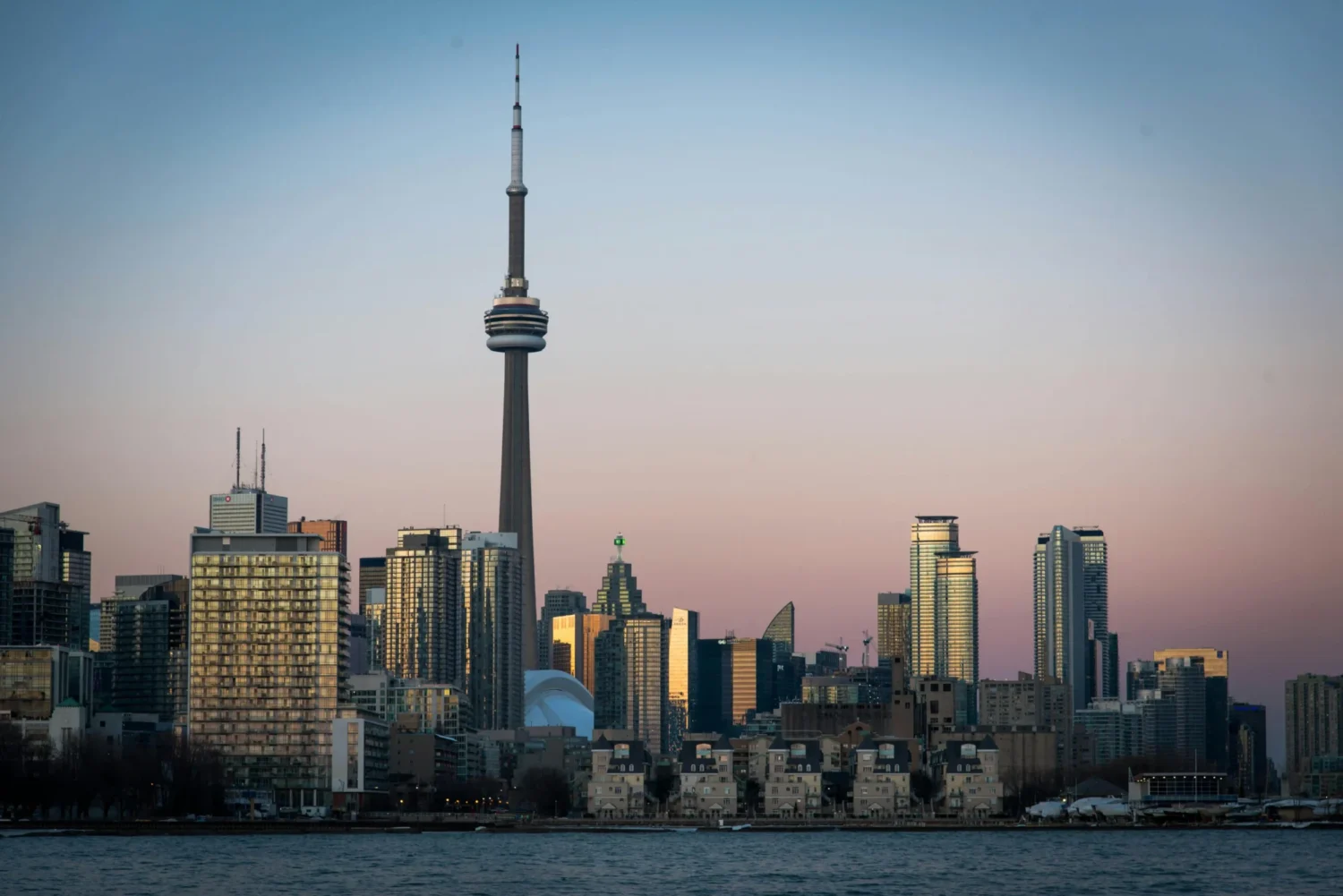CN Tower in Toronto at twilight, standing prominently above the city with evening sky in the background