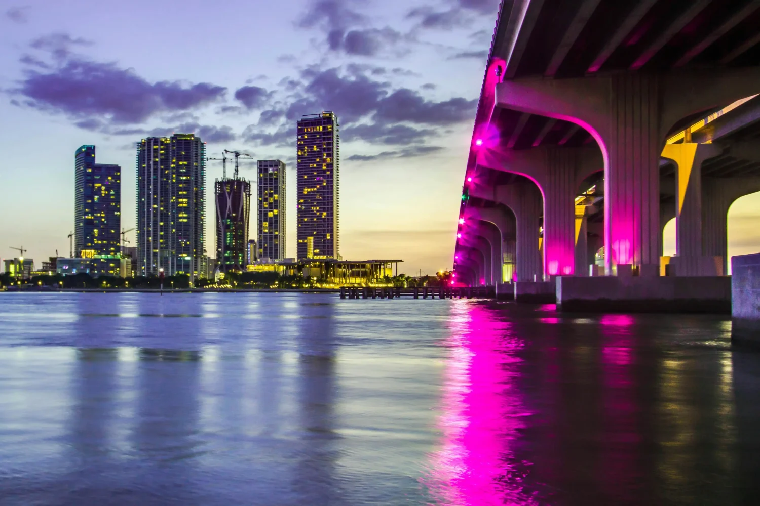 Miami skyline in the evening with colorful lighting reflecting off the buildings and water