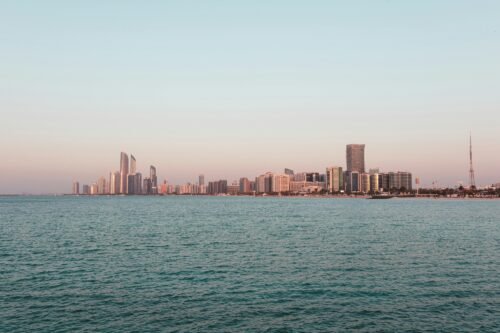 Doha, Qatar skyline along the coast with skyscrapers visible over the ocean during daylight