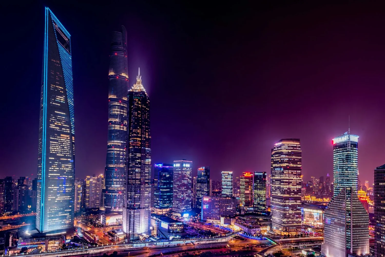 Shanghai Tower and Jin Mao Tower in Shanghai at night, glowing purple with surrounding city lights