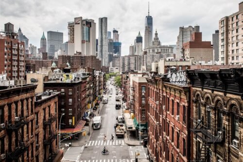 Lower Manhattan skyline in New York City with historic buildings and modern skyscrapers under a clear daytime sky
