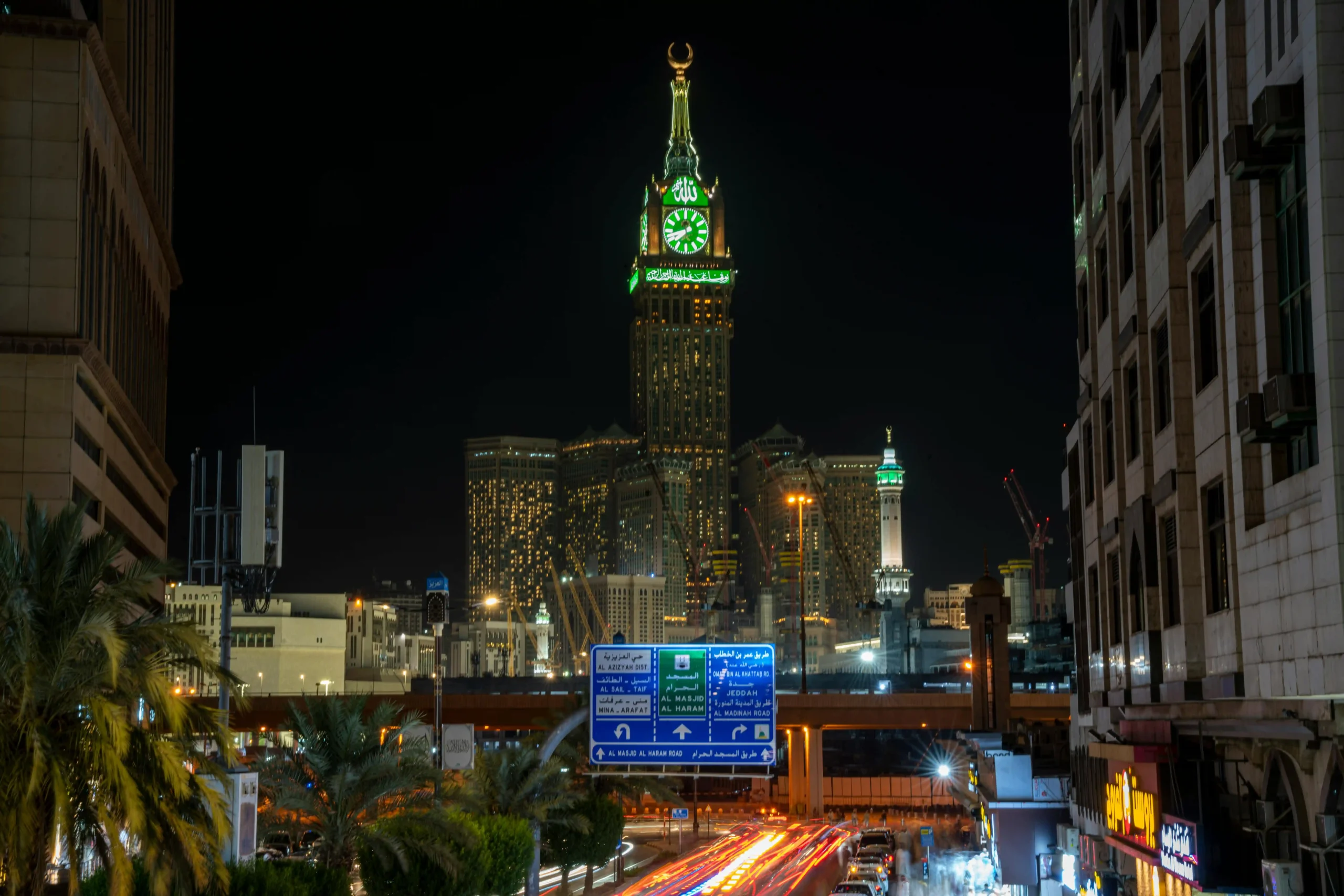10 Tallest Buildings in the World (2025) Night view of the Makkah Royal Clock Tower in Mecca, Saudi Arabia, illuminated with green lights, showcasing its prominent clock and decorative crescent at the top.